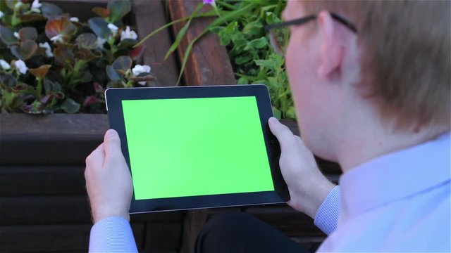 Man holds a blank digital tablet computer with a green screen