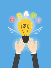 start your own business with creative ideas. hands of businessman holding glowing light bulb with colorful word BRAND