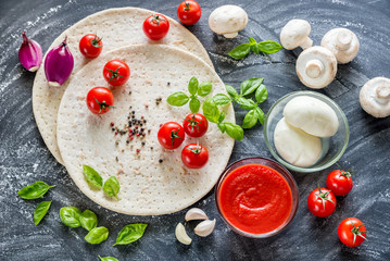 Pizza ingredients on the dark wooden background