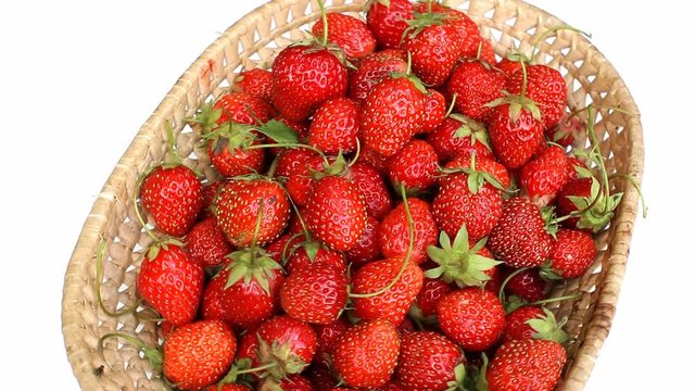 Wicker basket with strawberry rotates on white background
