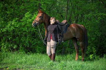 Beauty model girl in equestrian hunt uniform posing with horse 
