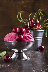 Cherry ice cream and cherries are on the wooden table.