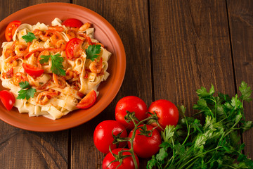 Fettuccine pasta with shrimp tomatoes and herbs. wooden background. Top view