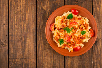 Fettuccine pasta with shrimp tomatoes and herbs. wooden background. Top view
