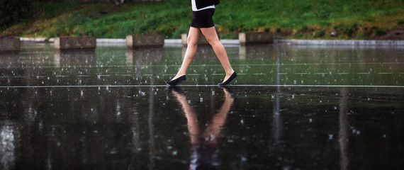 Woman legs and rain drops on asphalt
