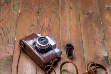 Old retro camera on vintage wooden boards abstract background. C