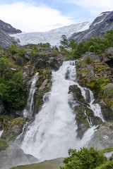 Briksdalsbreen glacier at summer with waterfall from melted ice on foreground. Jostedalsbreen National Park in Norway.