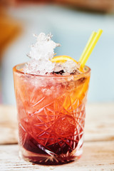Alcoholic cocktail consisting of currant, bramble, fresh lemon juice, sugar and liqueur in a glass beaker on a wooden table
