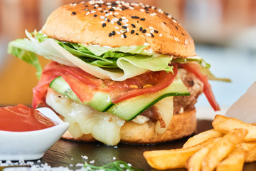 Fast food dinner of Burger, fries and a Cup of sauce, served on a stone Board