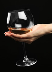 Fototapeta na wymiar Female hand holding glass of champagne on black background