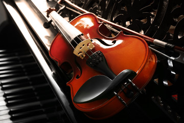 Fototapeta premium Violin lying on piano, close up
