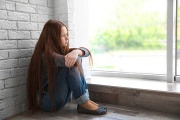 Sad girl sitting near window