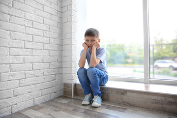 Sad boy sitting near window