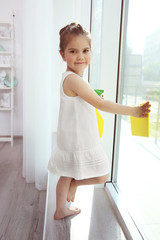Fototapeta na wymiar Cute little girl cleaning window