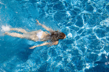 girl in a white bathing suit under the water in the pool