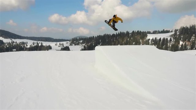 snowboard slow motion,following snowboarder jumping on kicker doing backside steadicam