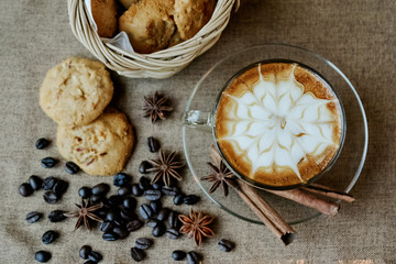 A cup of cafe latte with coffee beans and cookies
