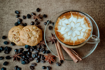 A cup of cafe latte with coffee beans and cookies