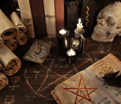 Magic book with pentagram, the tarot cards and candles on wooden planks