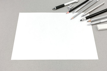 blank sheet of paper and drawing accessories on gray background