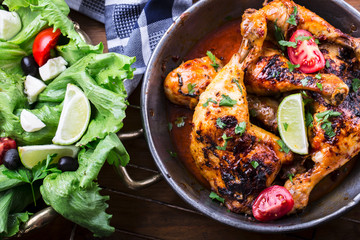 Grilled chicken legs, lettuce and cherry tomatoes limet olives. Traditional cuisine. Mediterranean cuisine.