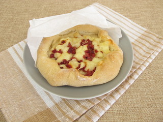 Pizzabrot Streetfood mit Käse und Schinken in einer Butterbrotpapier-Tüte