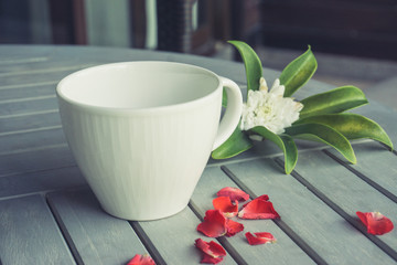 Empty cup and flowers on wooden table