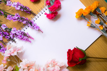 Fresh flower arrangements on book white page, lying on wooden table. Vintage style.