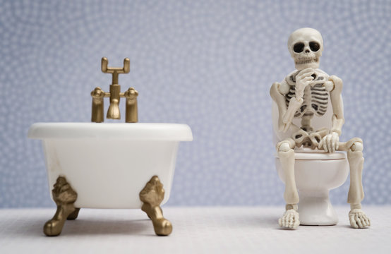 Skeleton thinking pose while sitting on water closet