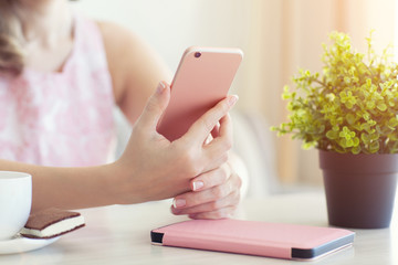 woman in summer cafe holding a pink phone