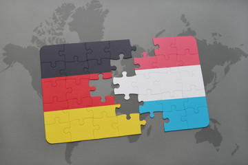puzzle with the national flag of germany and luxembourg on a world map background.