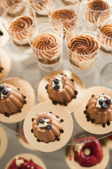 Delicious and tasty dessert table with cupcakes shots at reception closeup