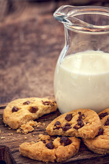 Chocolate chip cookies with milk in bottles on wooden background