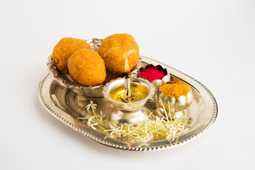 Beautifully Decorated Pooja Thali for diwali celebration to worship , having Indian sweets, silver lamp, flowers, huldi or turmeric powder and kumkum in a silver decorated plate