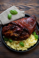 Frying pan with whole roasted pork knuckle and mashed potato