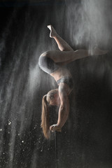 Woman gymnast handstand on equilibr while sprinkled flour