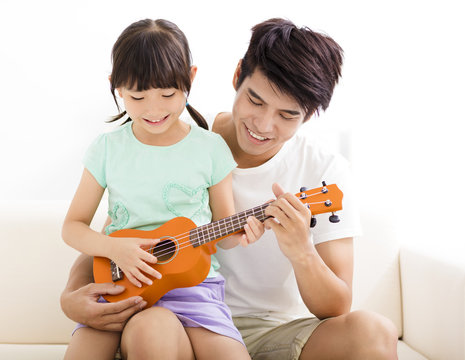 happy Father Teaching daughter To Play ukulele