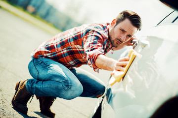 Young man cleaning his car outdoors