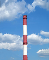Red and white colored stripe industrial smoke pipe on blue sky with white clouds vertical photo