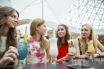 Close up four attractive young women drinking cocktails in shopp