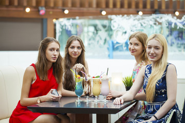 Close up four attractive young women drinking cocktails in shopp
