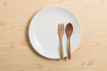 white circle plate on wood table with wood spoon and fork
