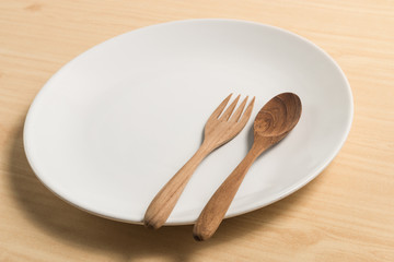 white circle plate on wood table with wood spoon and fork