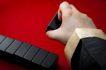 Croupier dealing the dominos on a red felt table background in the vintage casino game of Pai Gow...