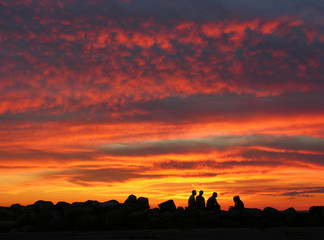 Fototapeta premium Menschen zum Sonnenuntergang am Abend auf einer Mole am Meer