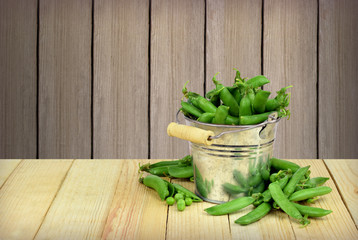 Pods of green peas in a bucket. The rustic style.
