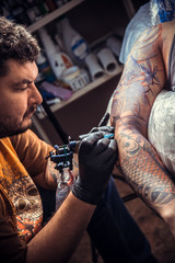 Tattoo specialist makes tattoo in tattoo parlor