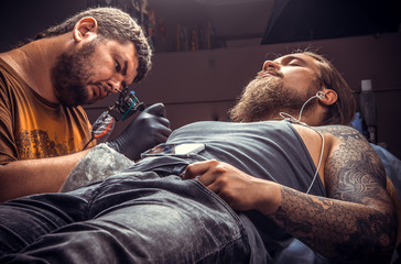 Fototapeta premium Professional tattooer working tattooing in tattoo parlor