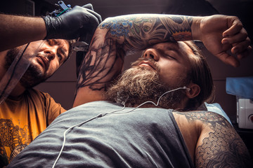 Professional tattooer works in tattoo parlor
