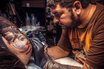 Tattoo specialist create tattoo in tattoo parlor